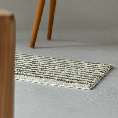 Olive green irregular stripe rug placed near wooden furniture legs - RoomDen