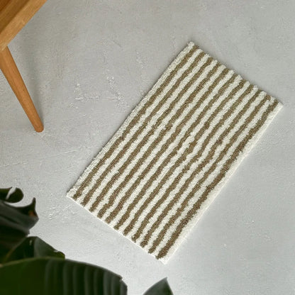 Top down view of olive and cream shaggy rug on grey background - RoomDen