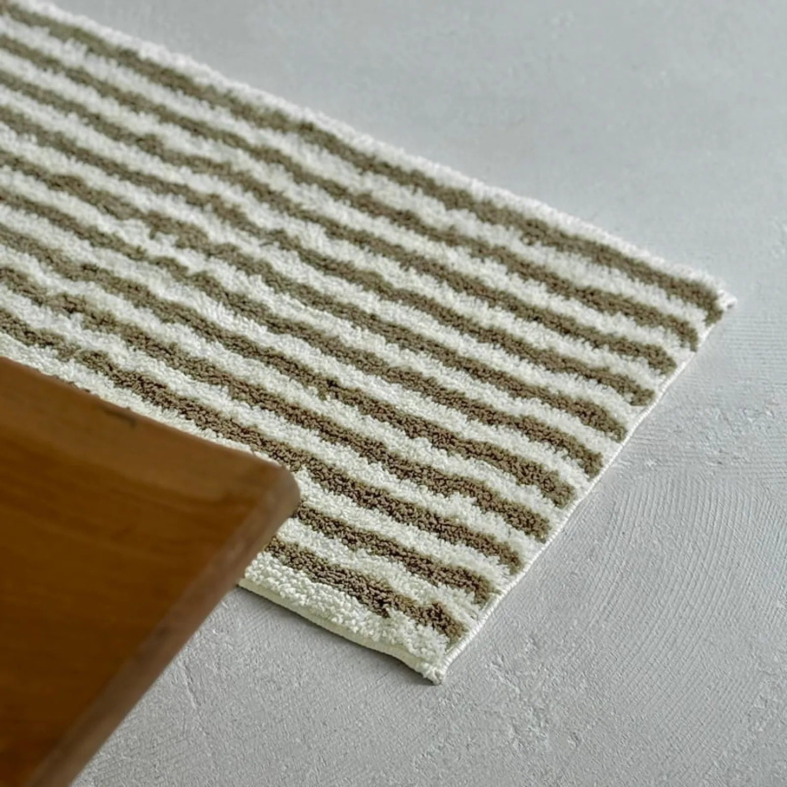 Close up of olive green wavy stripe texture next to wooden table - RoomDen