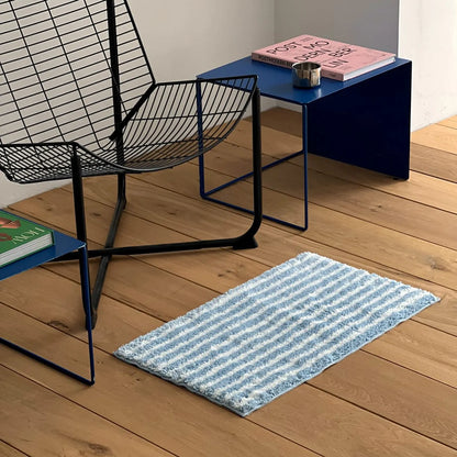 Blue and white wavy striped rug on wooden floor with modern blue table - RoomDen