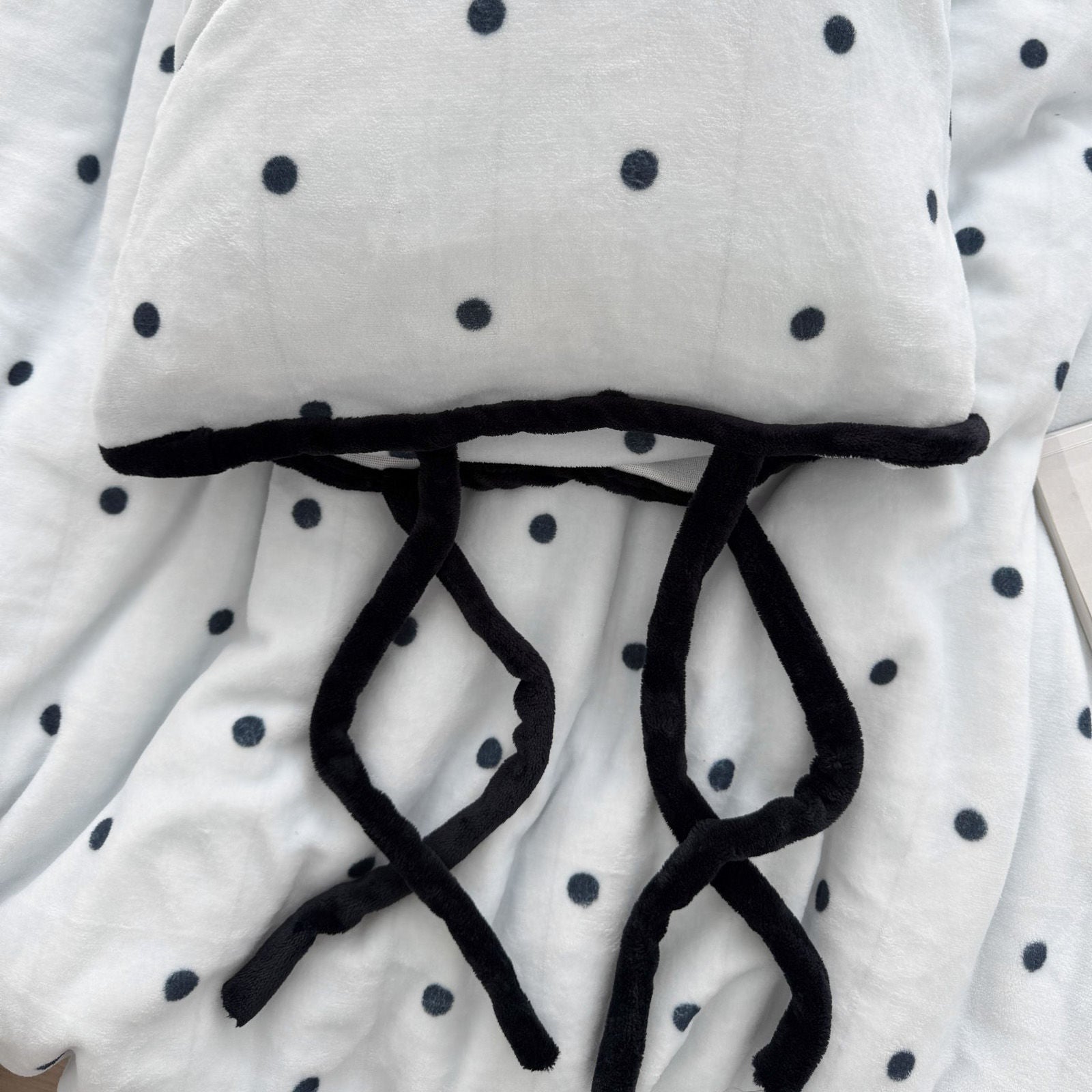 Detail shot of black bow tie closure on cream polka dot pillowcase RoomDen