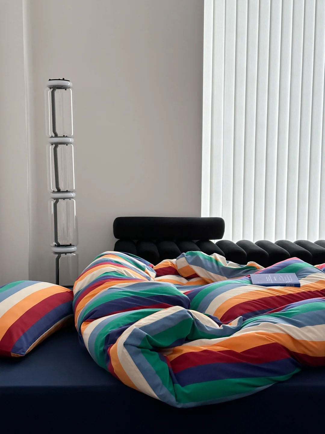 Colorful striped cotton bedding and pillow arrangement in minimalist room - RoomDen