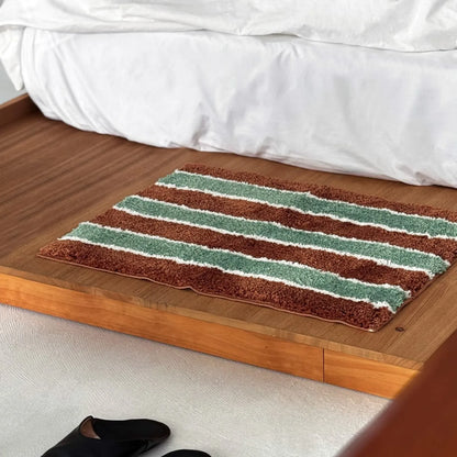 Angled view of a rectangular striped area rug placed next to a white bedding set.