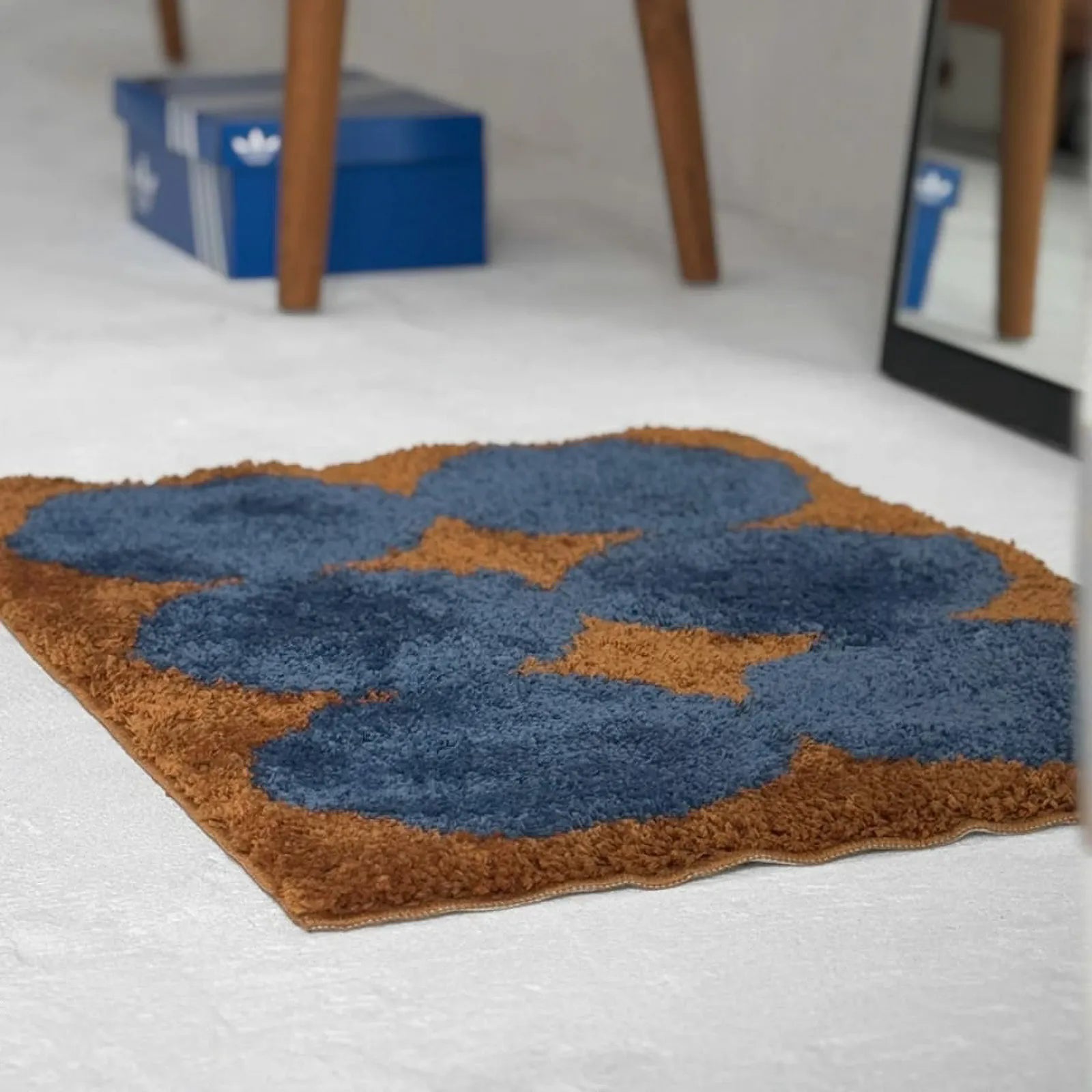 Eye-level view of retro blue and rust floral rug on white floor near furniture - RoomDen