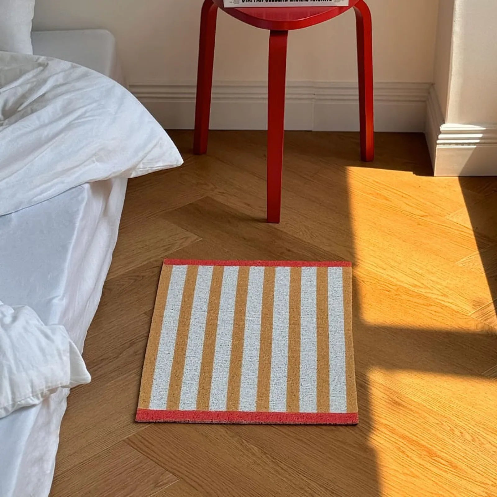 RoomDen yellow striped entrance mat styling shot with a red stool and natural light.