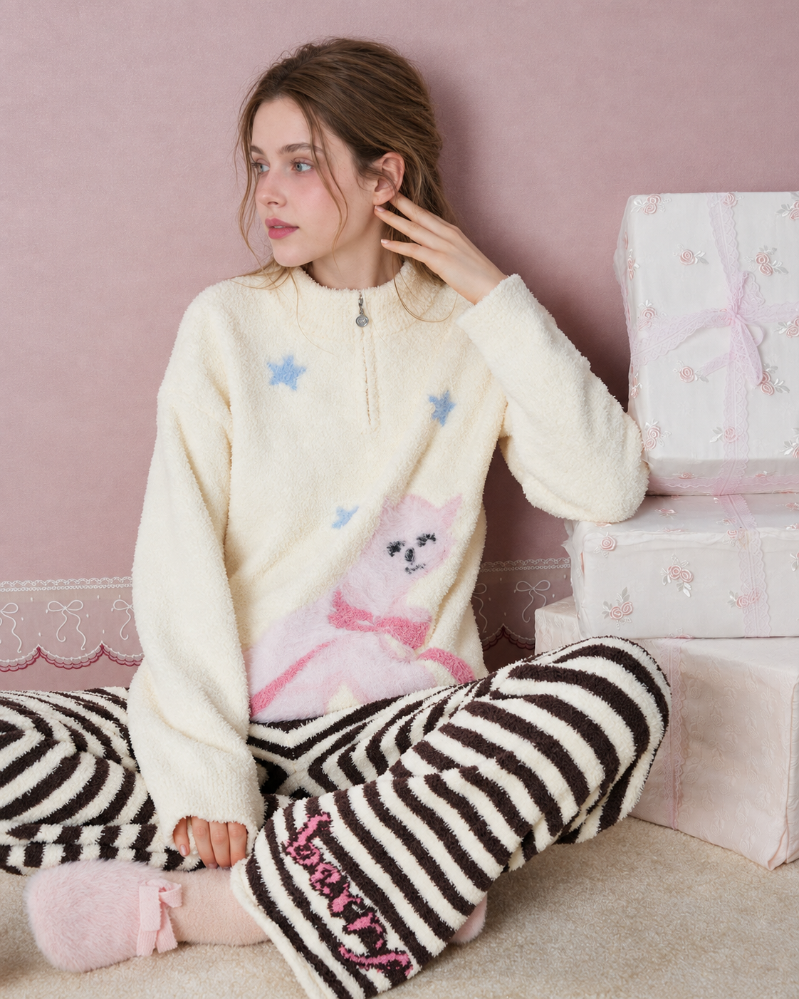 Cat and star plush pajama set shown sitting cross-legged beside gift boxes - Roomden