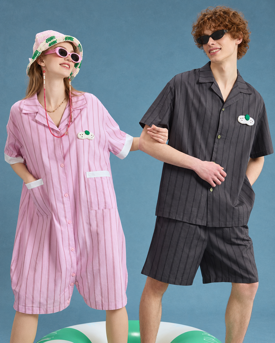 Pink striped cotton one-piece pajamas with white-trimmed pockets in a standing paired pose.
