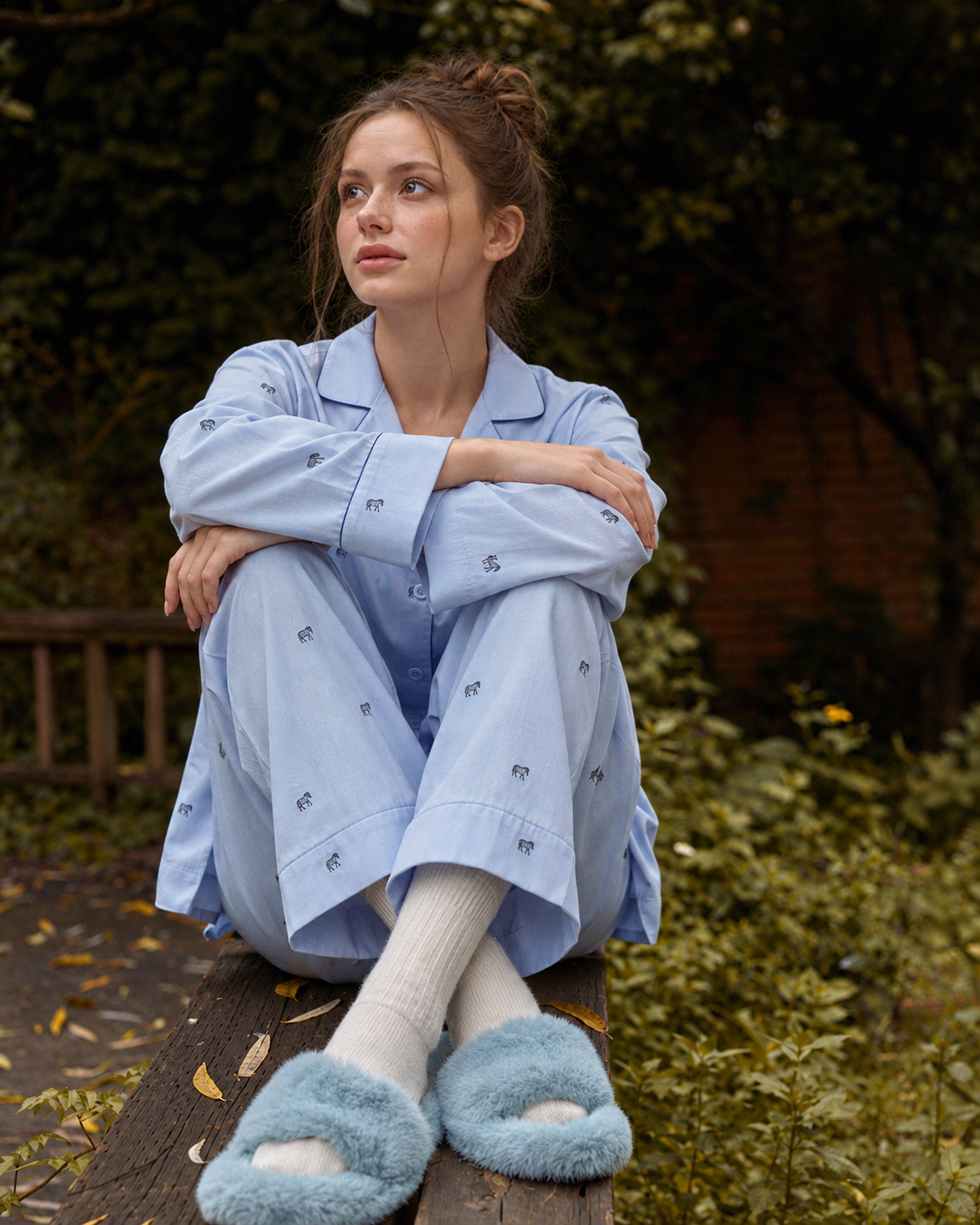 Animal-embroidered cotton pajama set in Sky Blue, seated on a wooden railing - Roomden
