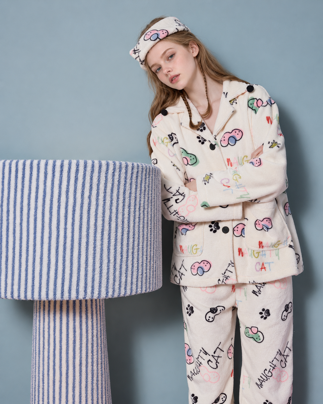 Doodlewhisk Cat Doodle Fleece Pajama Set – cream pajama set with black buttons beside a striped lamp - Roomden