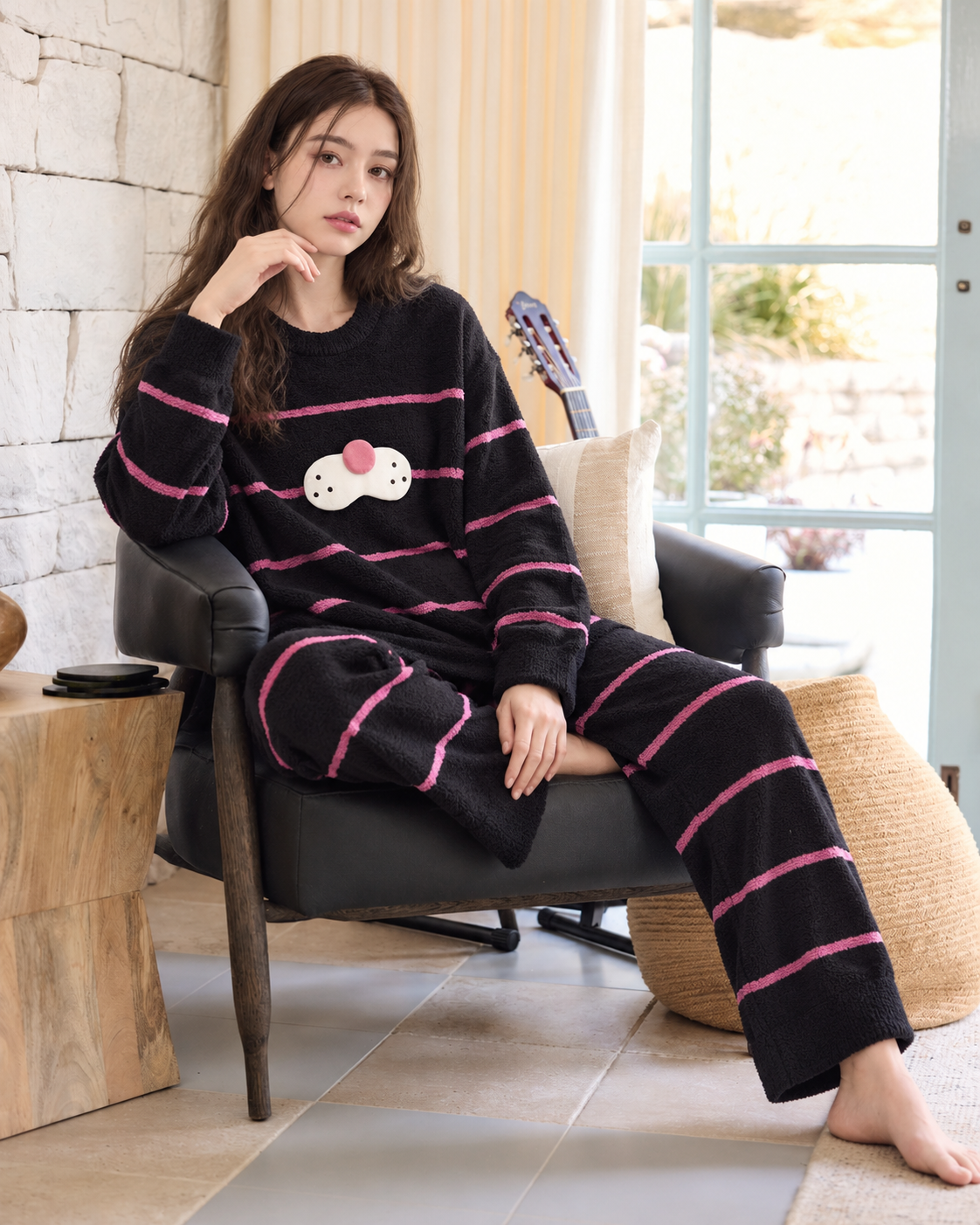 Black striped plush cat pajama set shown on a model relaxing indoors.