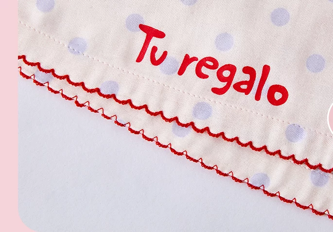 Close-up of red embroidered lettering and scalloped shorts hem - Roomden