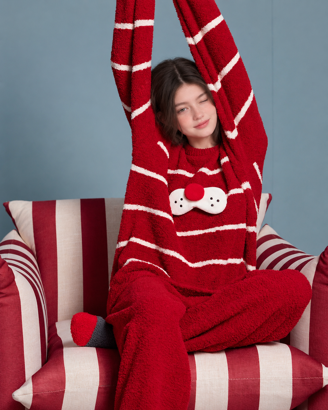 Red striped plush cat pajama set shown on a model relaxing indoors.