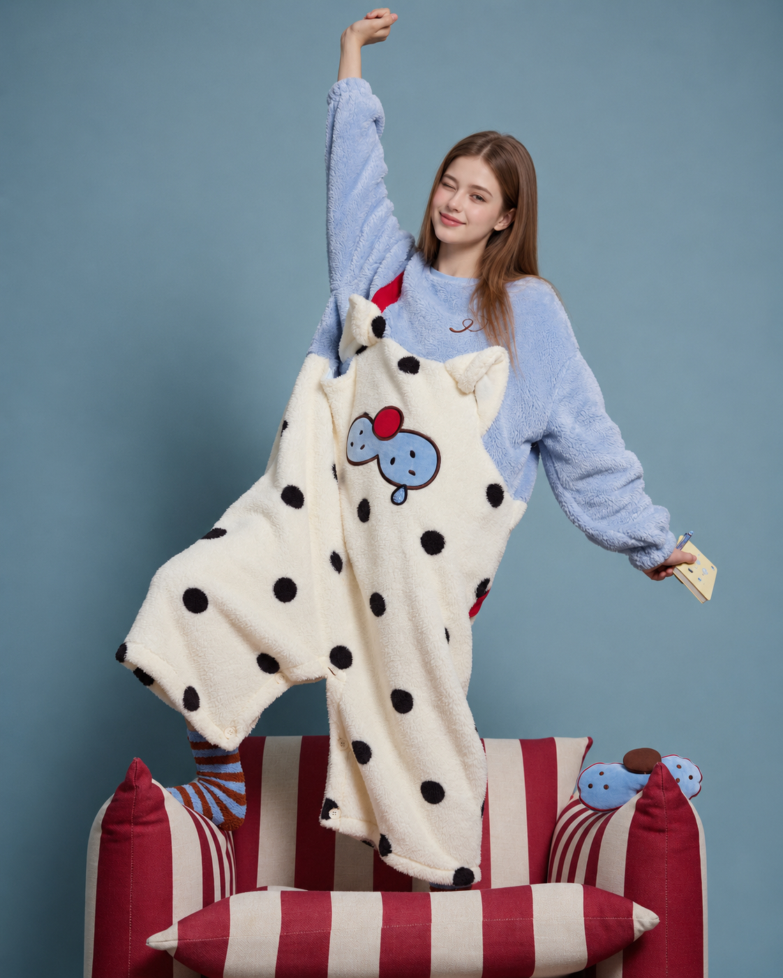 Cat Face Polka Dot Plush Onesie – blue and cream, raised-arm pose on an armchair - Roomden