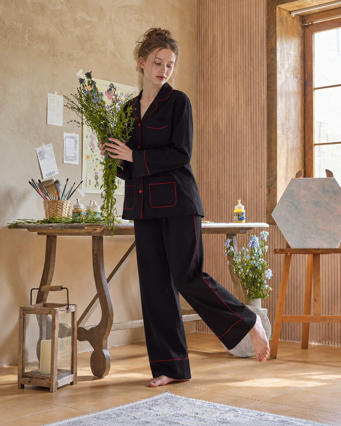 Linehaven contrast-piped pajama set in black, holding flowers in a creative studio - Roomden