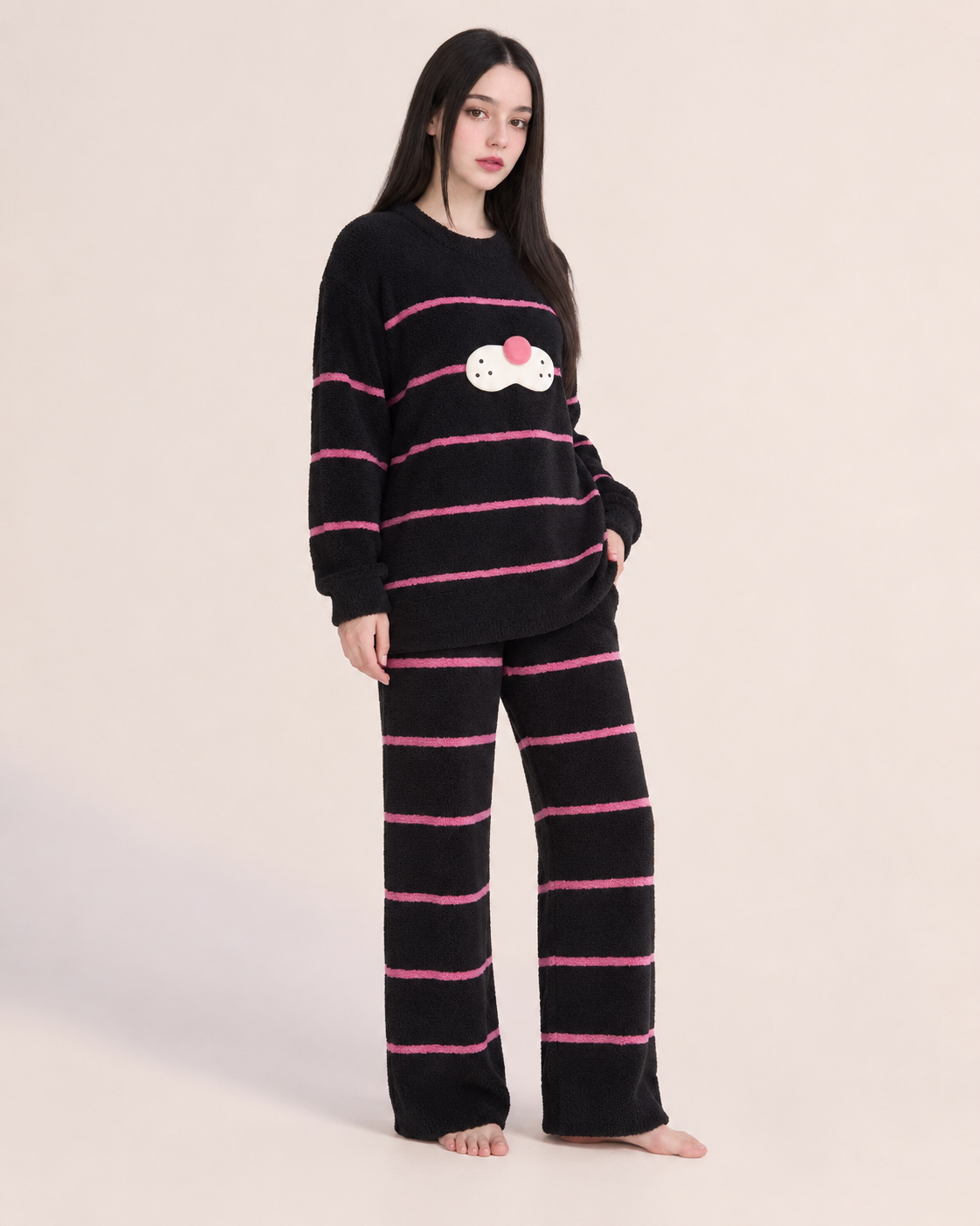 Black striped plush cat pajama set shown on a model in a studio.
