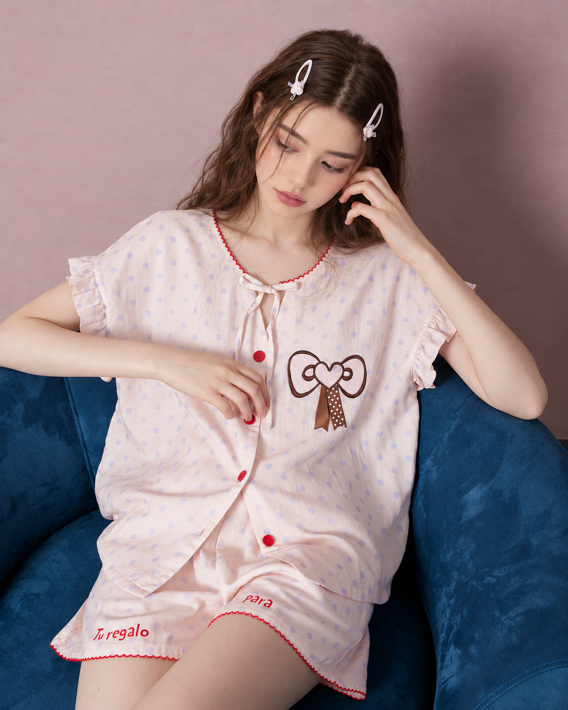 Seated view of pearl pink polka-dot pajamas with red trim - Roomden