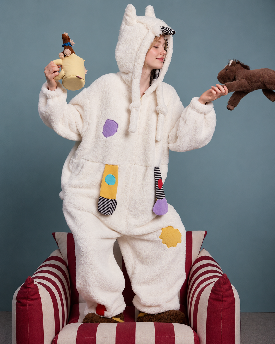 Pony Hood Fleece One-Piece Pajamas – playful pose with two pony toys beside a striped chair - Roomden