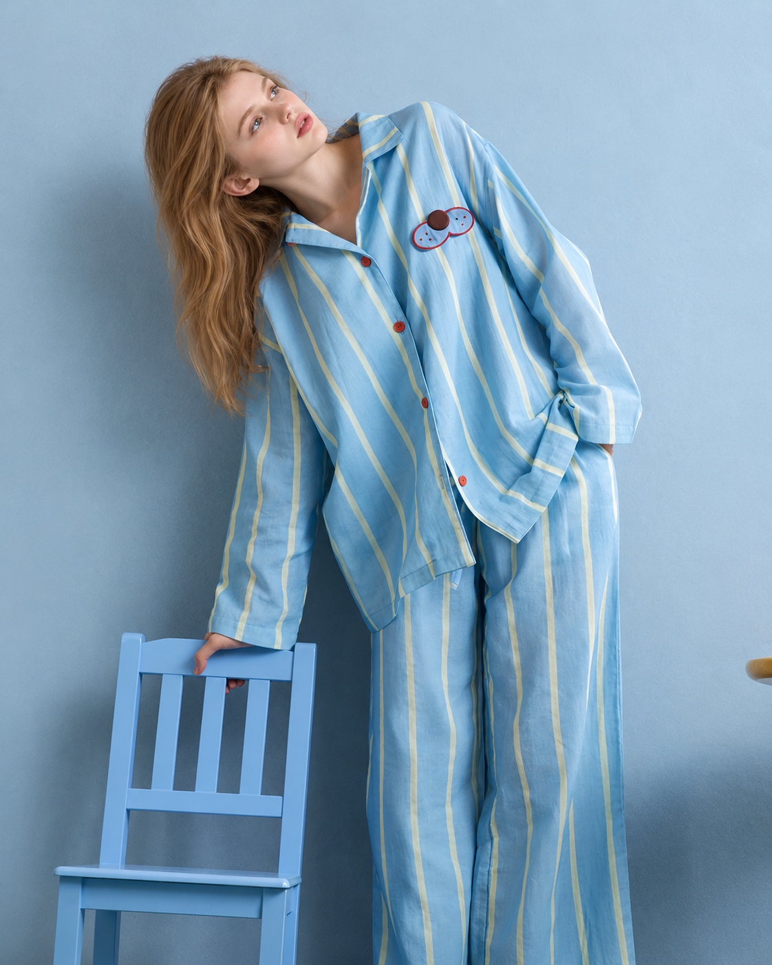 Striped Cotton Pajama Set – blue, yellow and white leaning pose beside a blue chair - Roomden