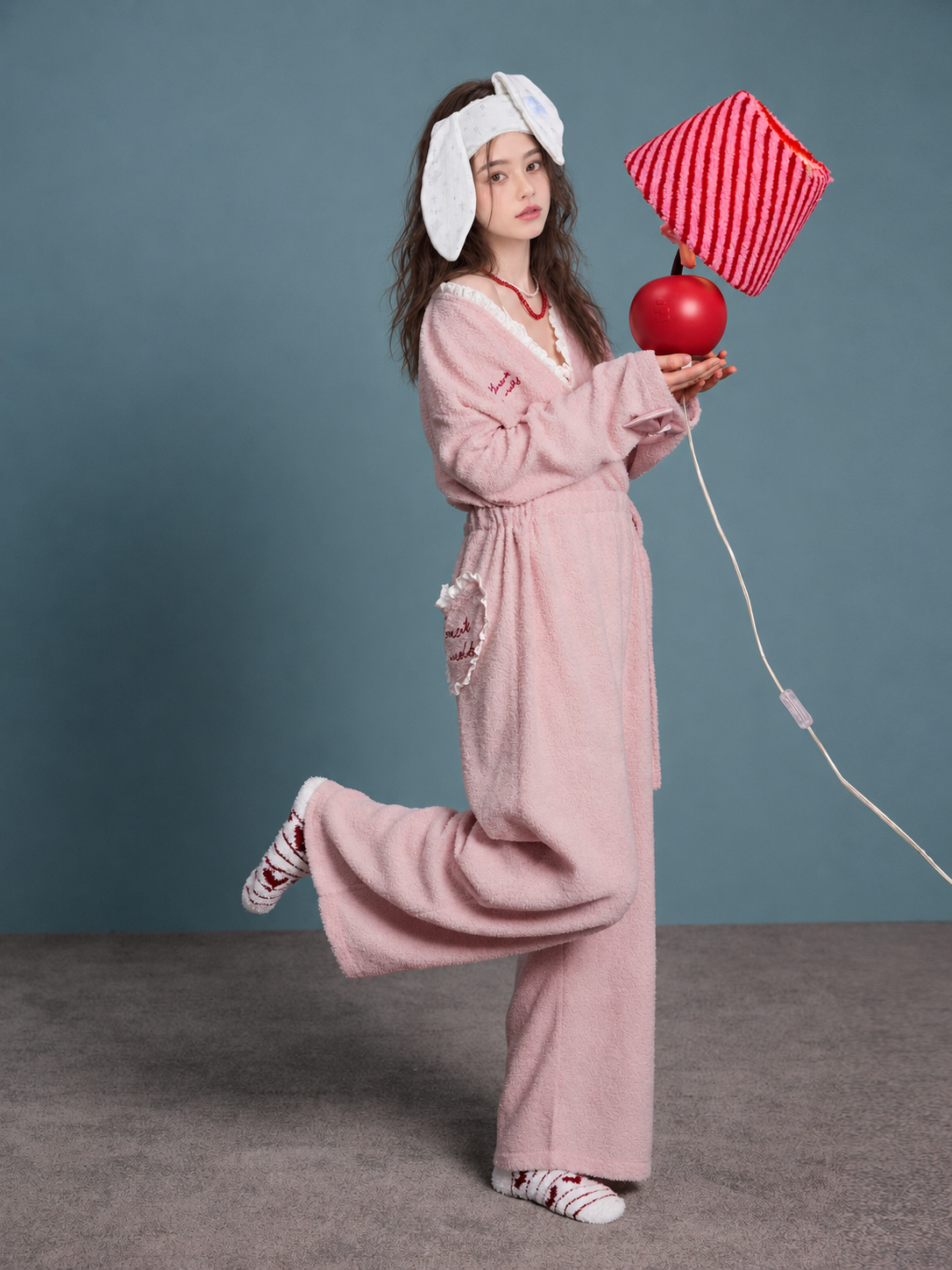 Blush Pink Plush Onesie – raised-leg pose with props - Roomden