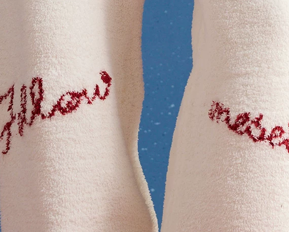Pom-Pom Fleece Pajama Set – ivory close-up of red script lettering on ivory fleece trousers - Roomden