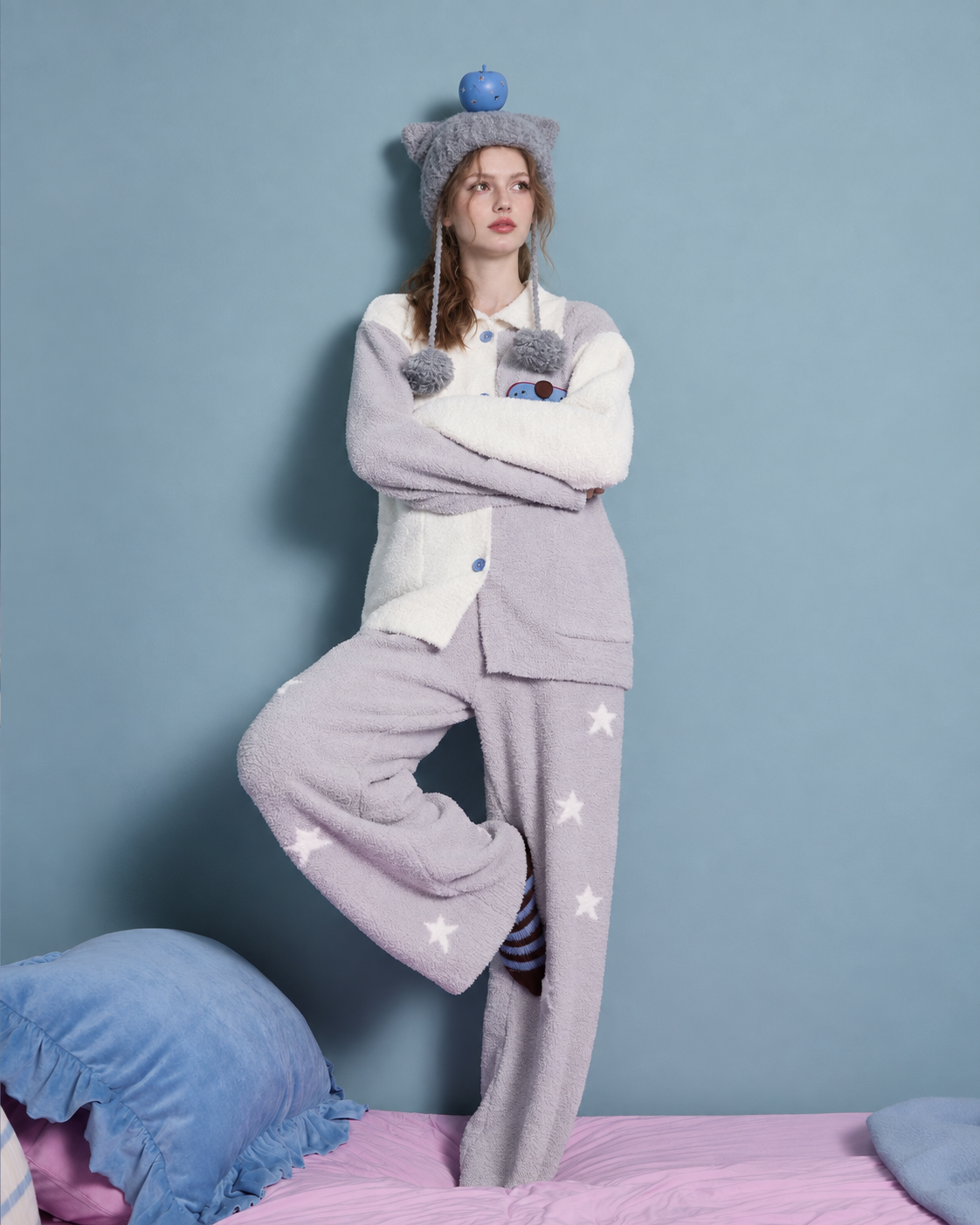 Colorblock star fleece pajama set – gray-and-white raised-leg pose beside blue and pink bedding - Roomden