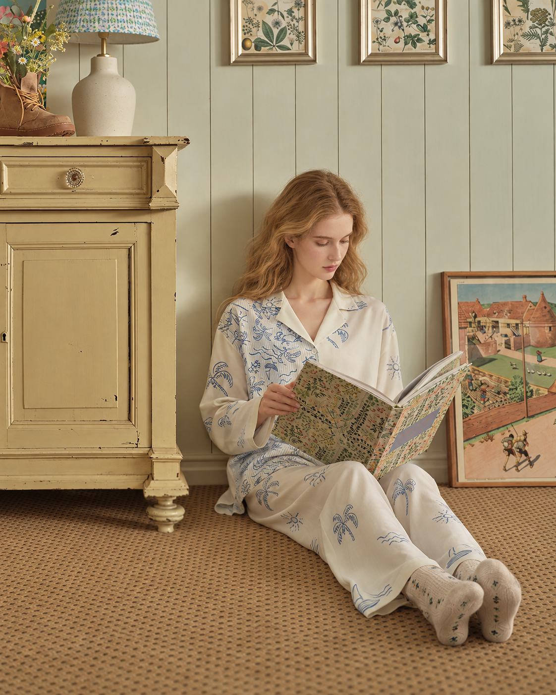 Inkshore asymmetric coastal-print viscose pajama set in Apricot Cream, reading beside a vintage cabinet - Roomden