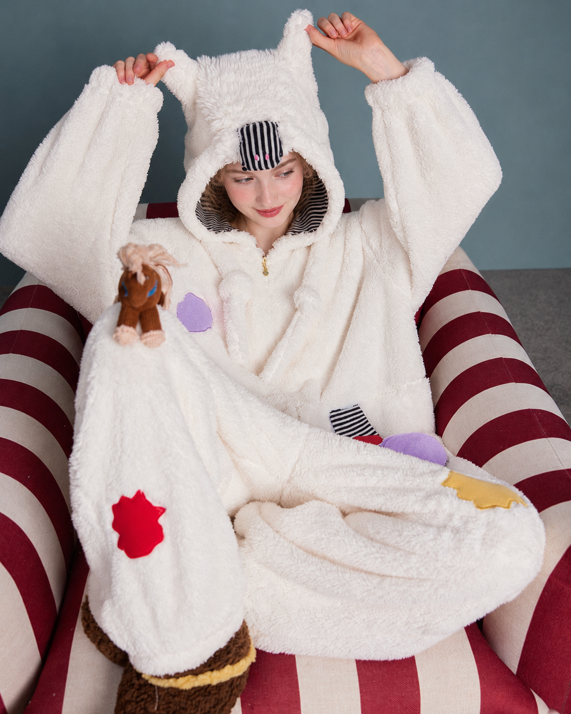 Pony Hood Fleece One-Piece Pajamas – cross-legged pose holding the pony hood ears - Roomden