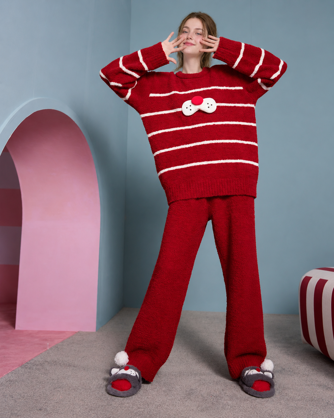 Red striped plush cat pajama set shown on a model in a studio.