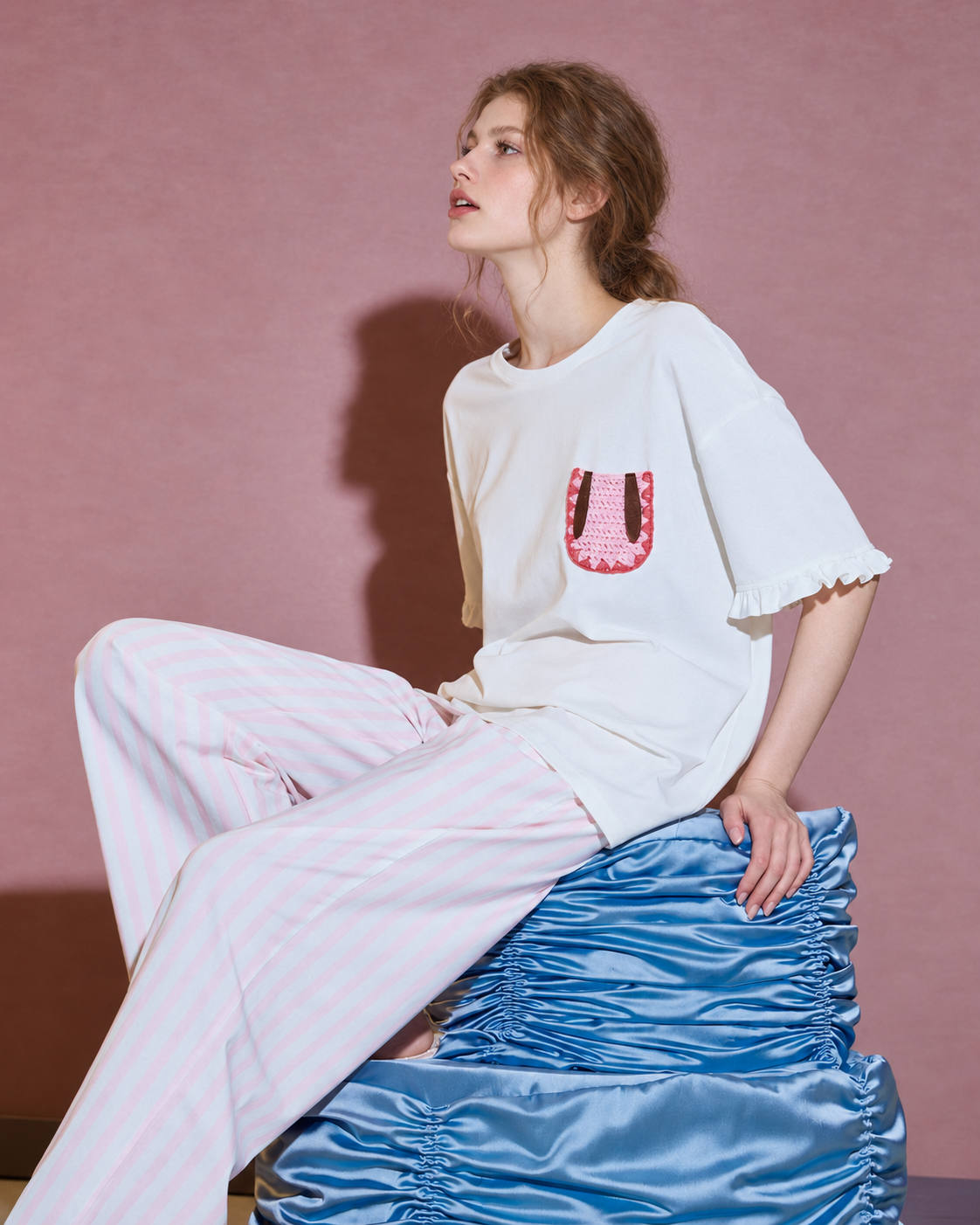 Side seated view of the pajama set against a pink wall