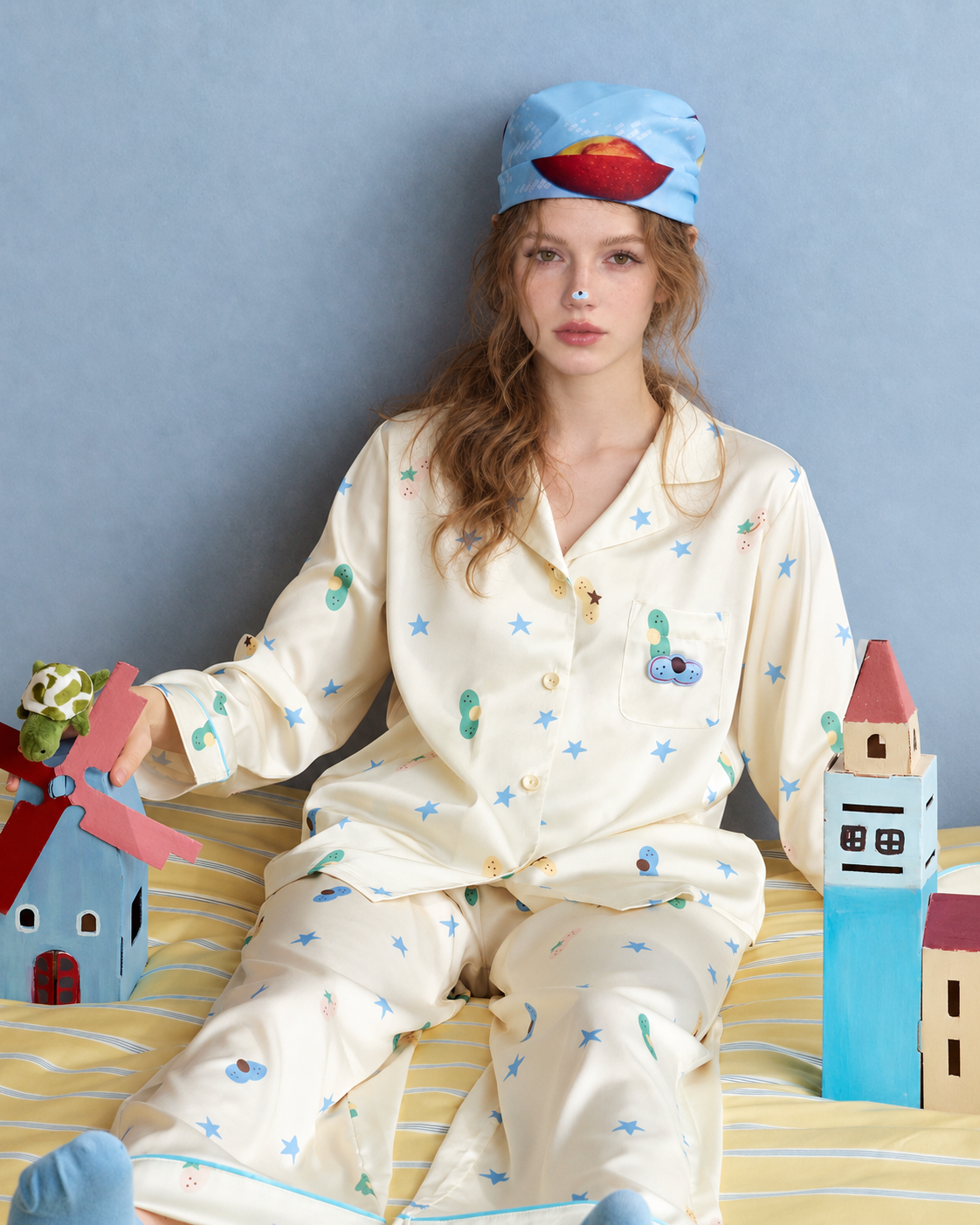 Cat & Star Satin Pajama Set – pale yellow seated on a striped bed - Roomden