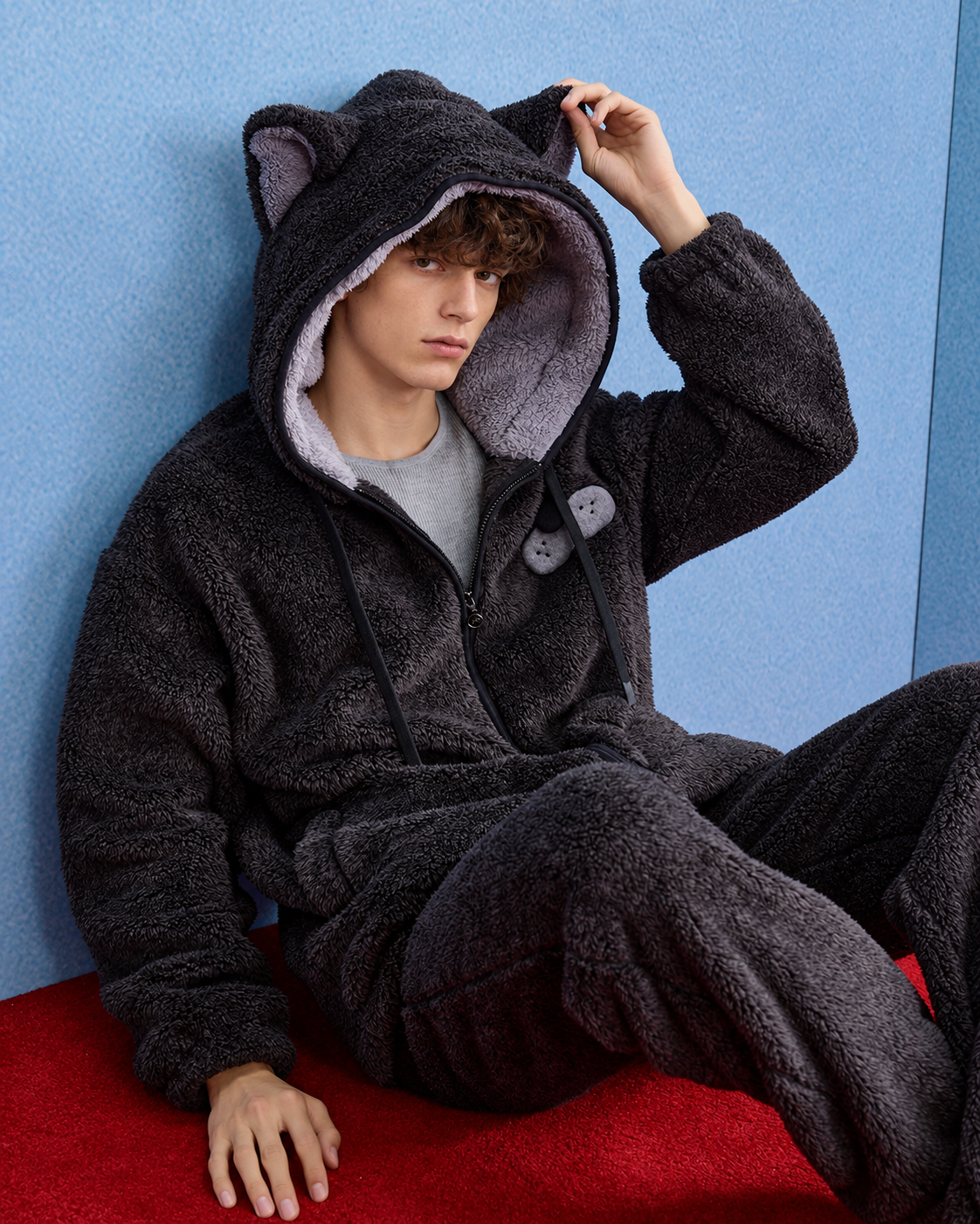 Men's Cat-Ear Hooded Fleece Pajama Set – dark gray seated on a red sofa - Roomden