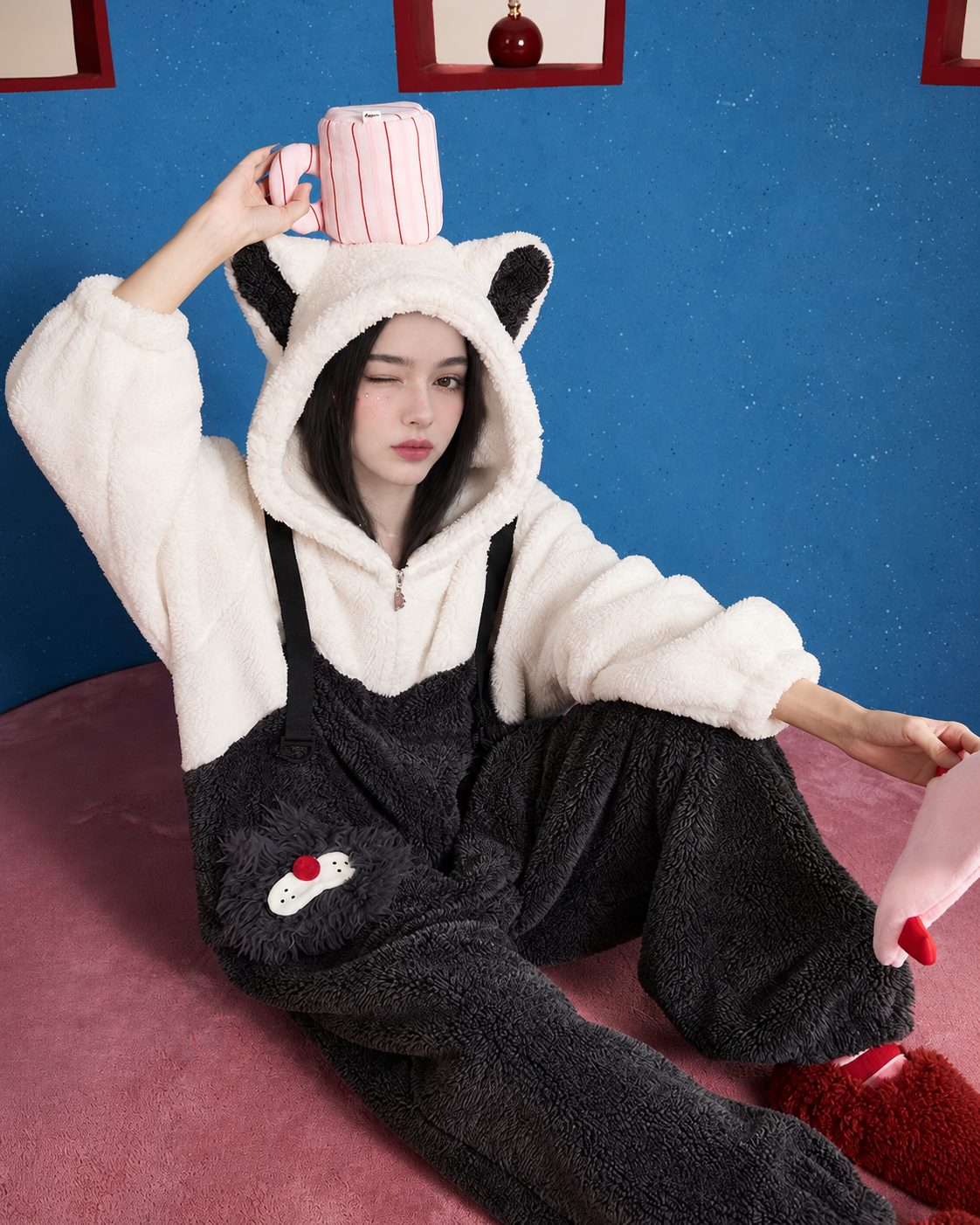 Seated view of black-and-white cat-ear one-piece pajamas