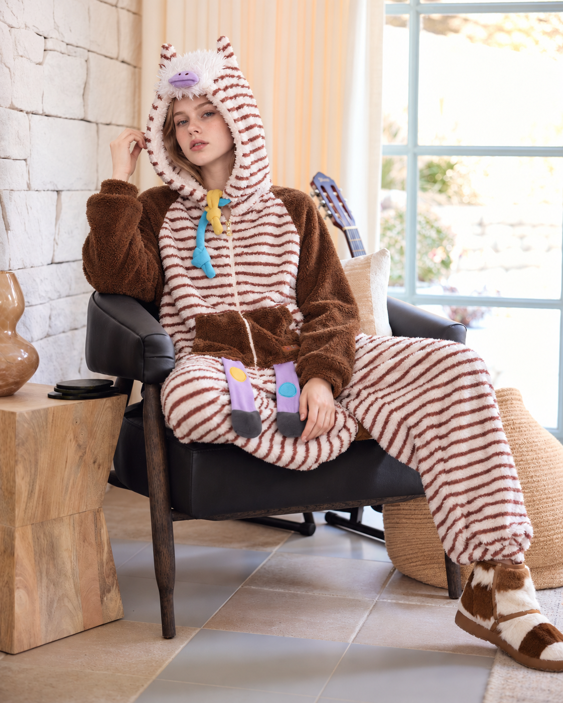 Striped Horse-Hood Onesie – seated window-side pose with raised hand - Roomden