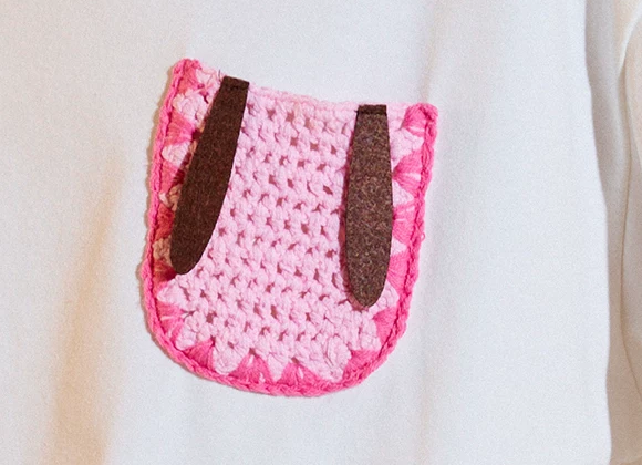 Close-up of the pink crochet rabbit pocket and dark drooping ears