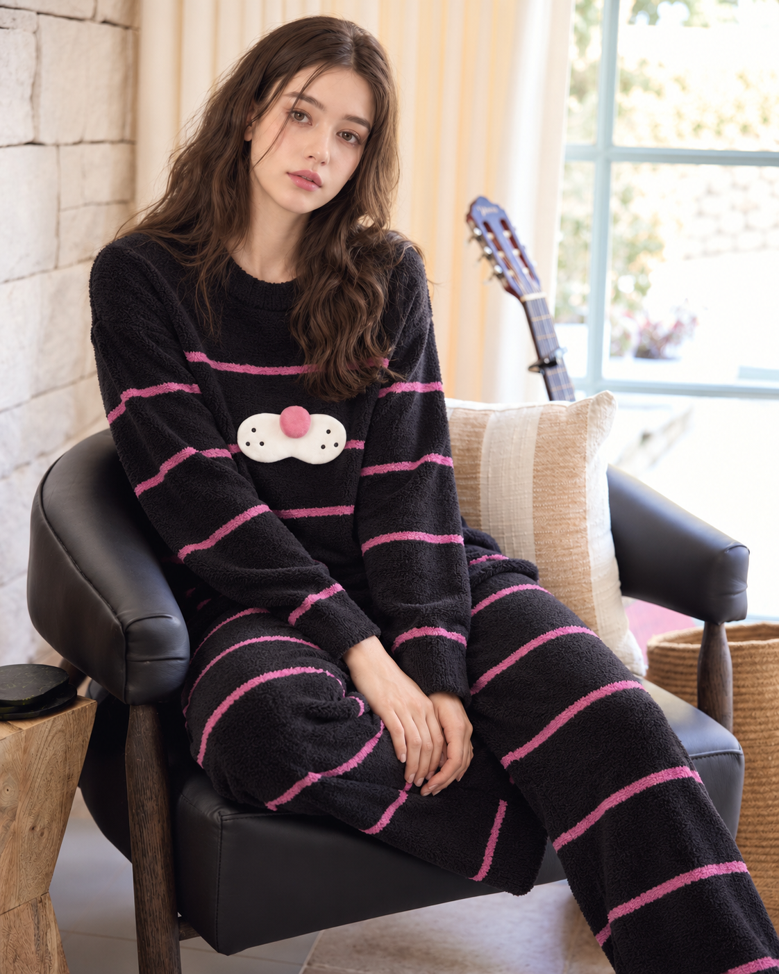 Black striped plush cat pajama set shown on a model relaxing indoors.