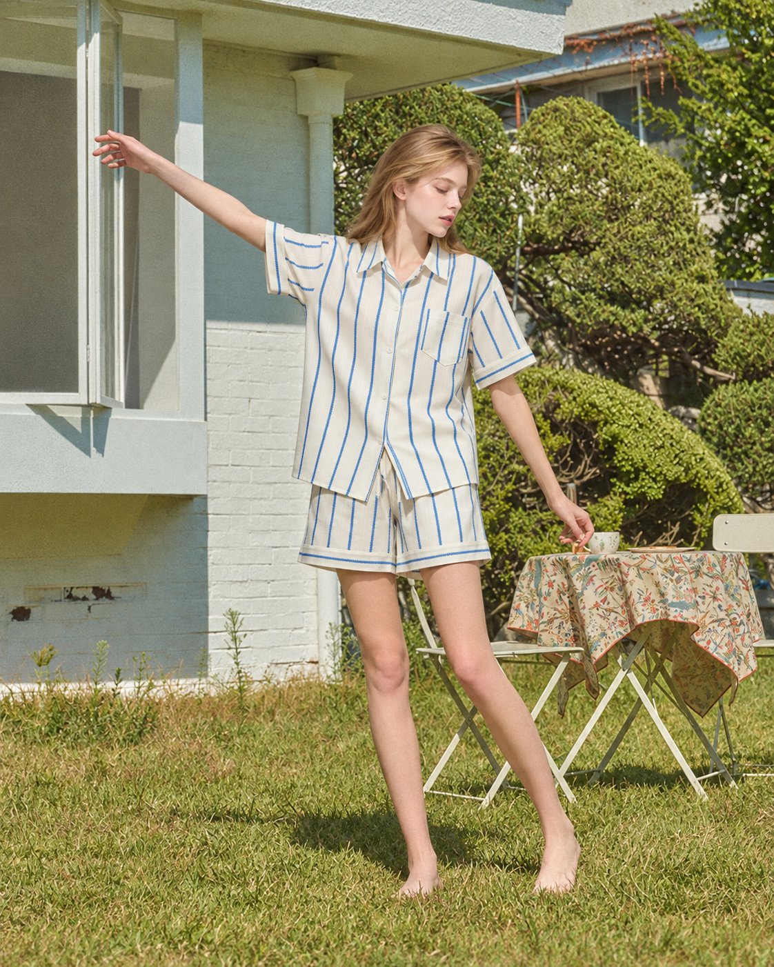 Slateway striped cotton pajama shorts set in blue & white, standing in a sunny garden - Roomden