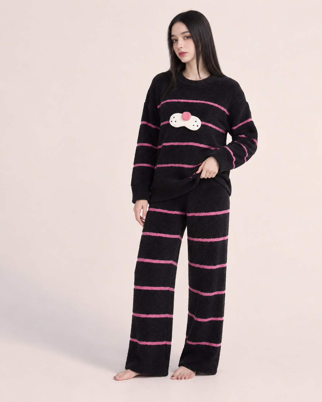 Black striped plush cat pajama set shown on a model in a studio.