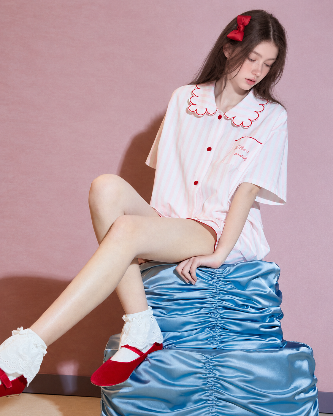 Scalloped collar striped cotton pajama set – pink and white, crossed-leg view on blue satin props - Roomden