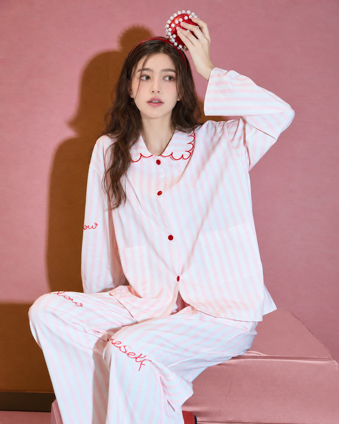 Scalloped Stripe Cotton Pajama Set – seated with one hand raised beside a pearl-trimmed prop - Roomden
