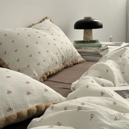 High angle view of the duvet cover and pillows with all-over bow print and pom poms