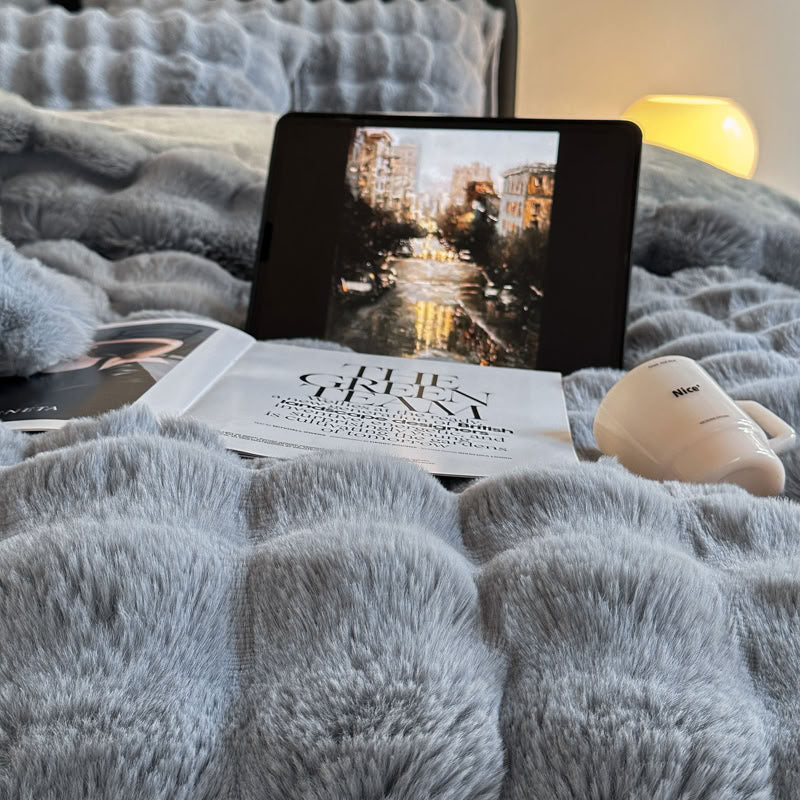Close-up of grey blue faux fur bedding with tablet and cozy details – RoomDen