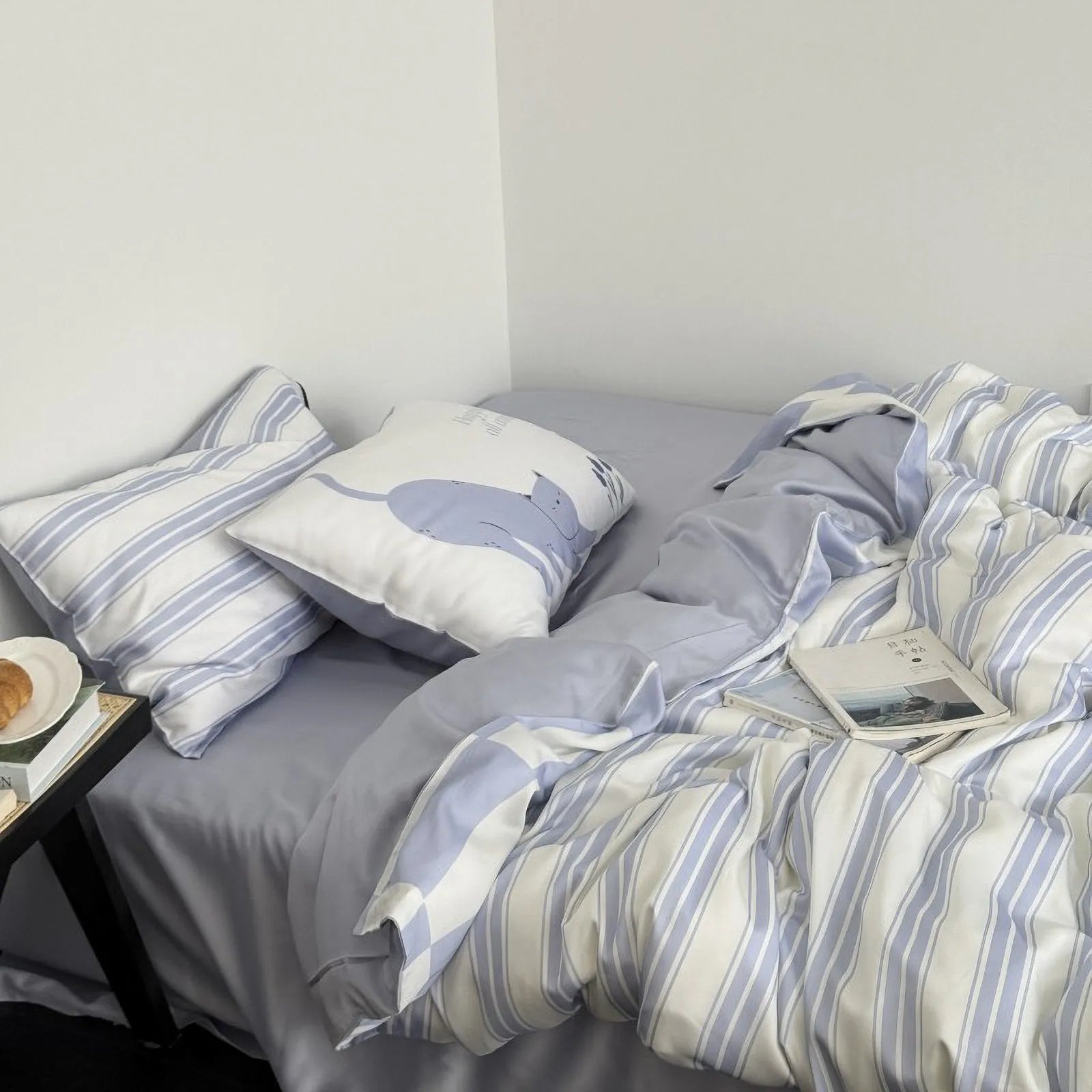 Messy bed look showing the reversible plaid pattern on the duvet cover and striped sheets.