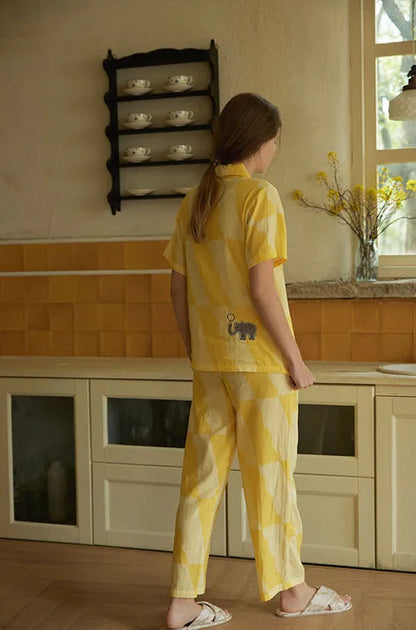 Woman wearing sunny yellow washed cotton pajama set with playful elephant patch, relaxed homewear look – RoomDen