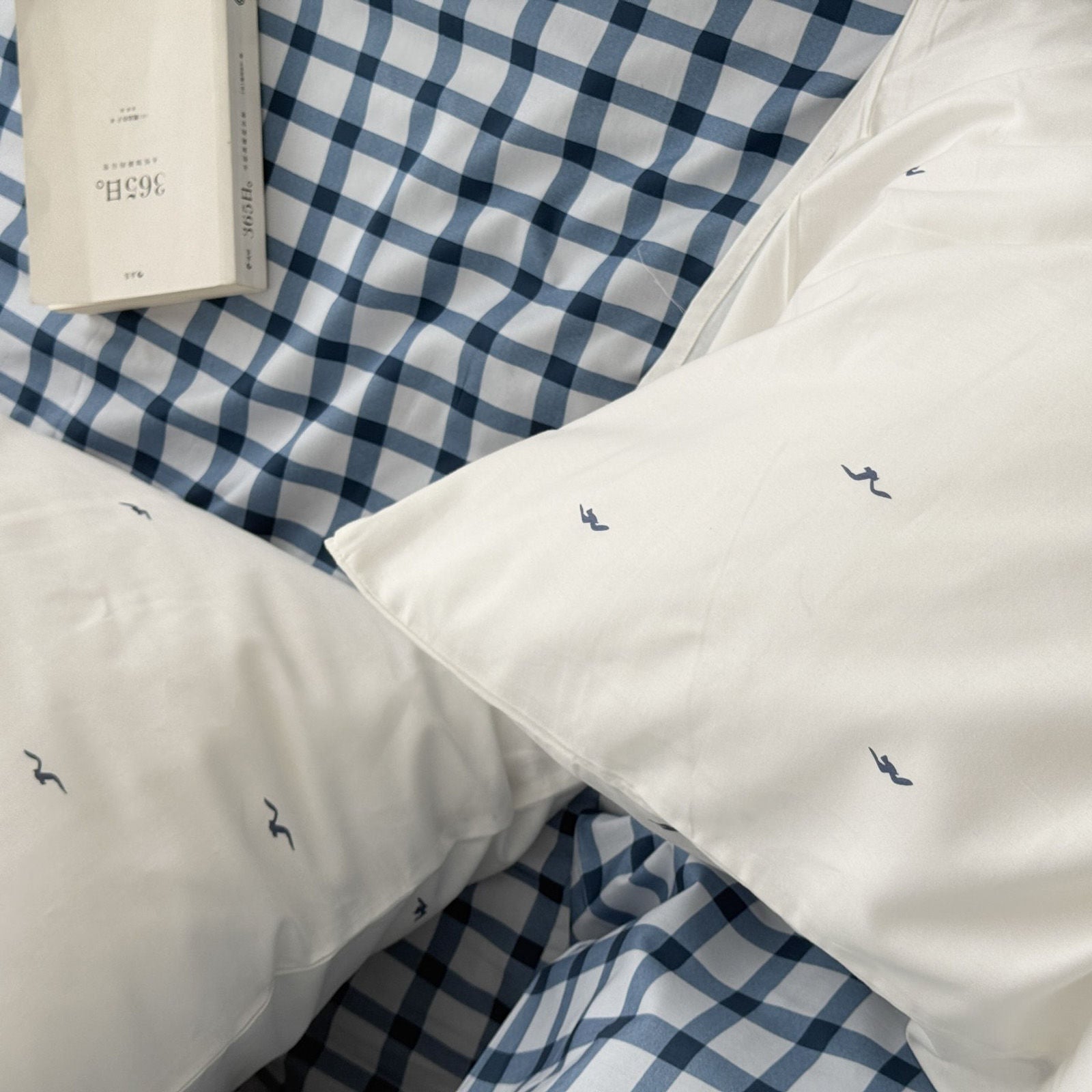 Top down view of soft bedding texture, highlighting the contrast between white duvet and blue grid sheet