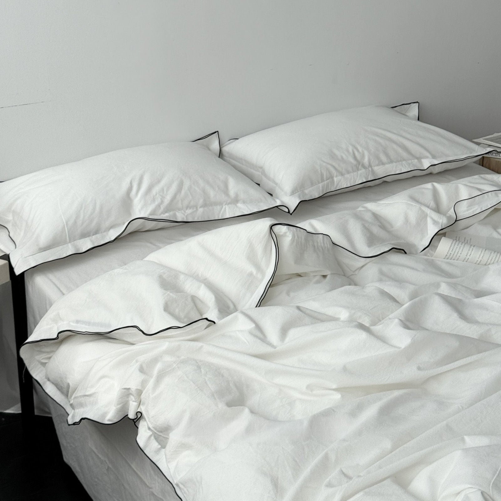 Close up of soft white duvet cover texture with black trim edges on pillows RoomDen