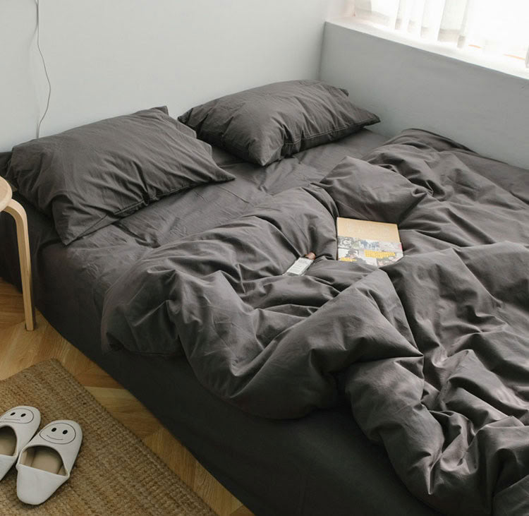 Brown grey washed cotton bedding set with matching pillows on a low bed beside the window - RoomDen  