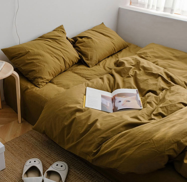 Mustard yellow washed cotton bedding set with matching pillows and a book on the bed - RoomDen