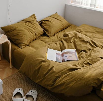 Mustard yellow washed cotton bedding set with matching pillows and a book on the bed - RoomDen