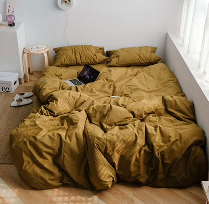Warm mustard yellow washed cotton bedding set in a minimalist bedroom with wooden floor and sunlight - RoomDen