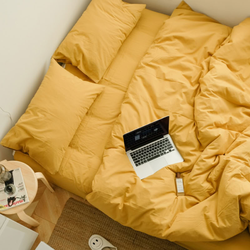Bright sunny yellow washed cotton bedding set in a cozy minimalist bedroom with natural light - RoomDen